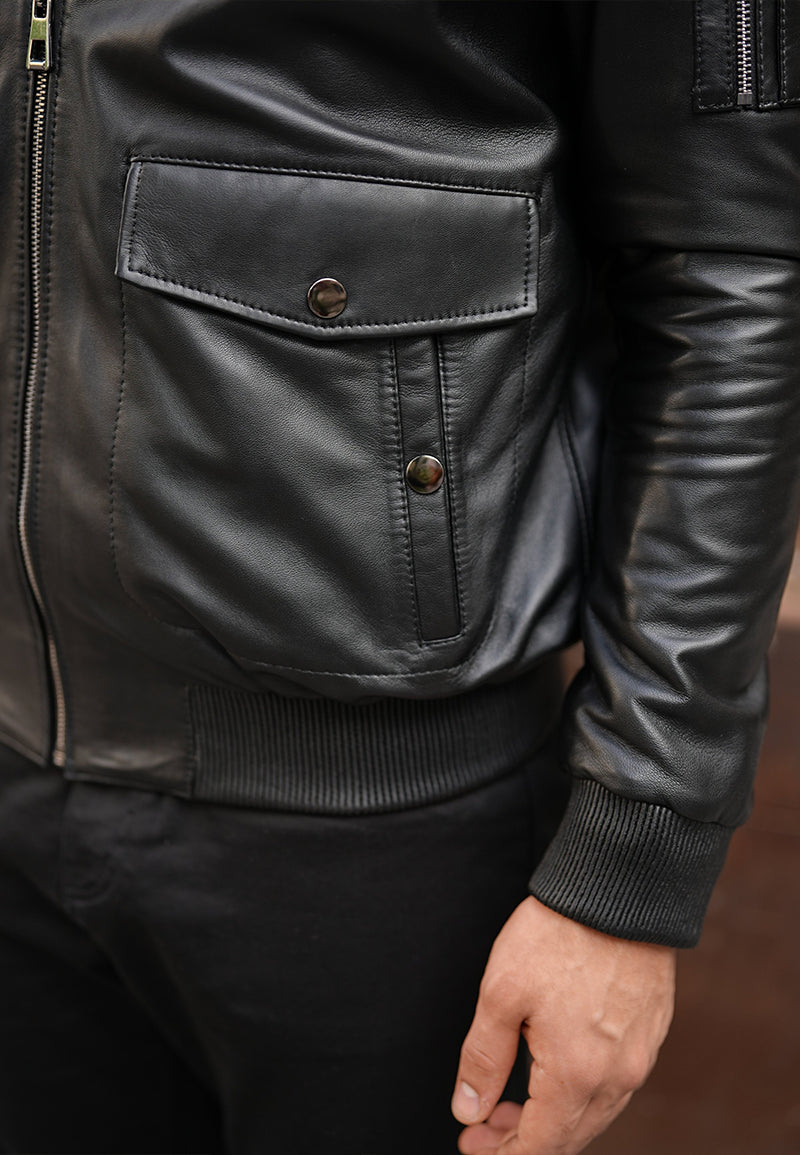 Close-up of a black sheepskin shearling coat, a leather jacket with buttons, and a zipper.