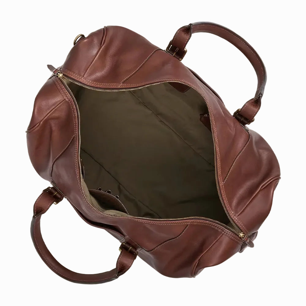 Vintage Brown leather travel and gym duffel bag with gold buckles on a beige background