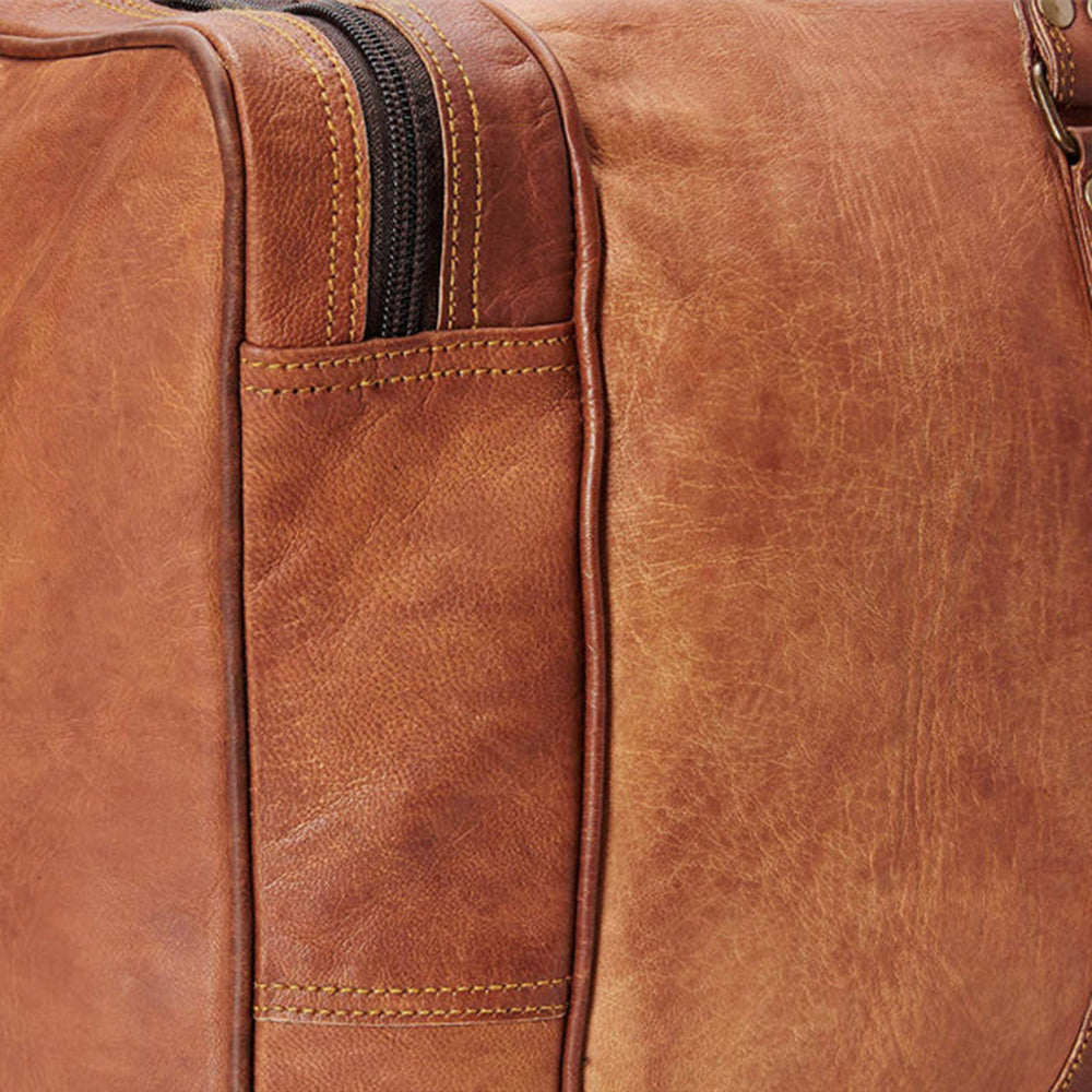 Close-up of a brown leather duffle bag with visible stitching