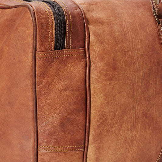Close-up of a brown leather duffle bag with visible stitching