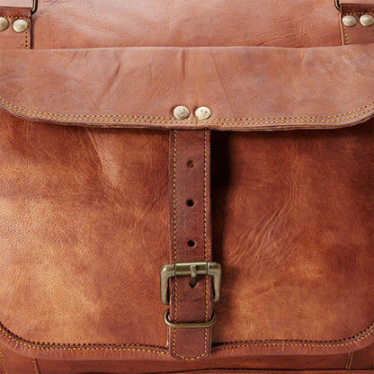 Close-up of a brown leather travel duffle bag with a strap and buckle.