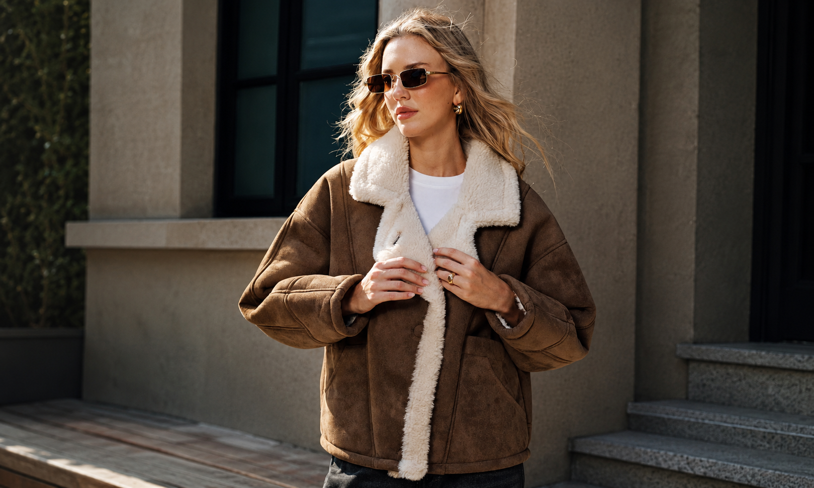 A woman wearing a brown sheepskin leather shearling jacket in an urban setting