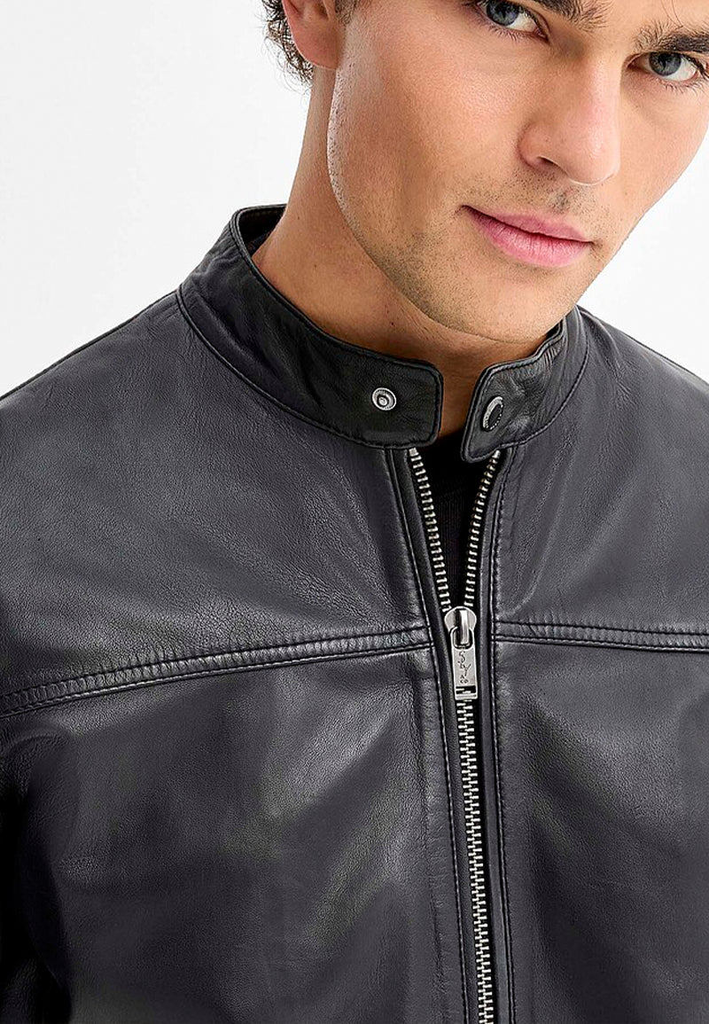 Close-up of a person wearing a black leather jacket with a zipper.