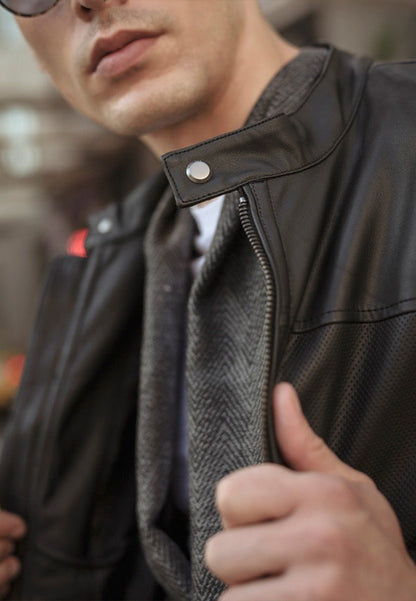 Close-up of a person wearing a black sheepskin leather jacket with a blurred background