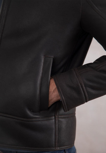 Close-up of a person wearing a brown genuine leather shearling jacket with a neutral background