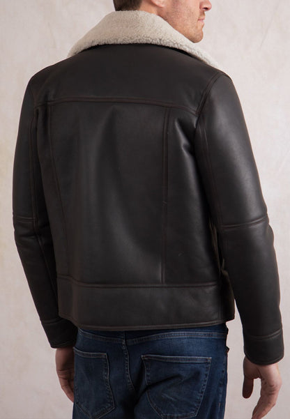 A brown shearling leather jacket worn by a man on a plain background