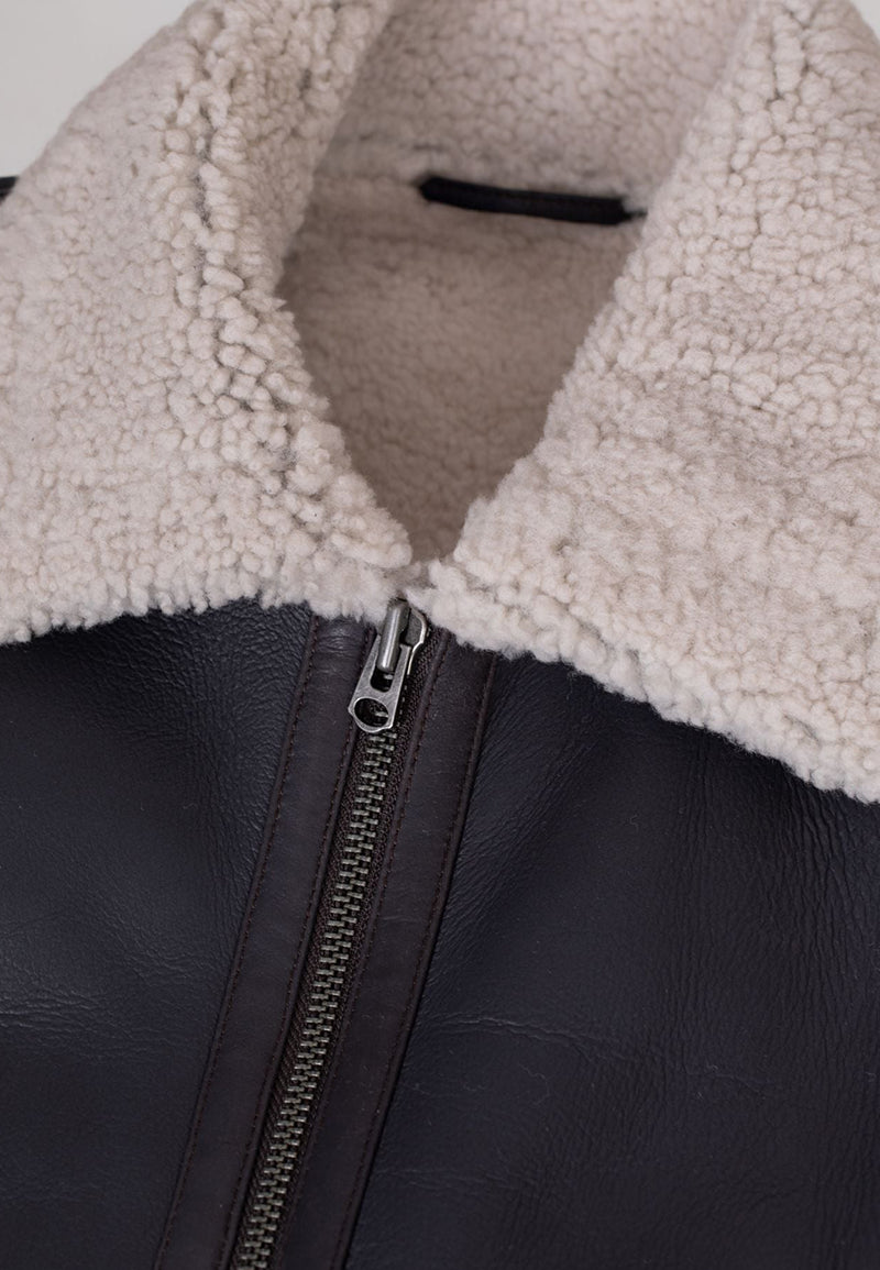 Close-up of a brown men's leather shearling jacket with a sherpa lining and zipper