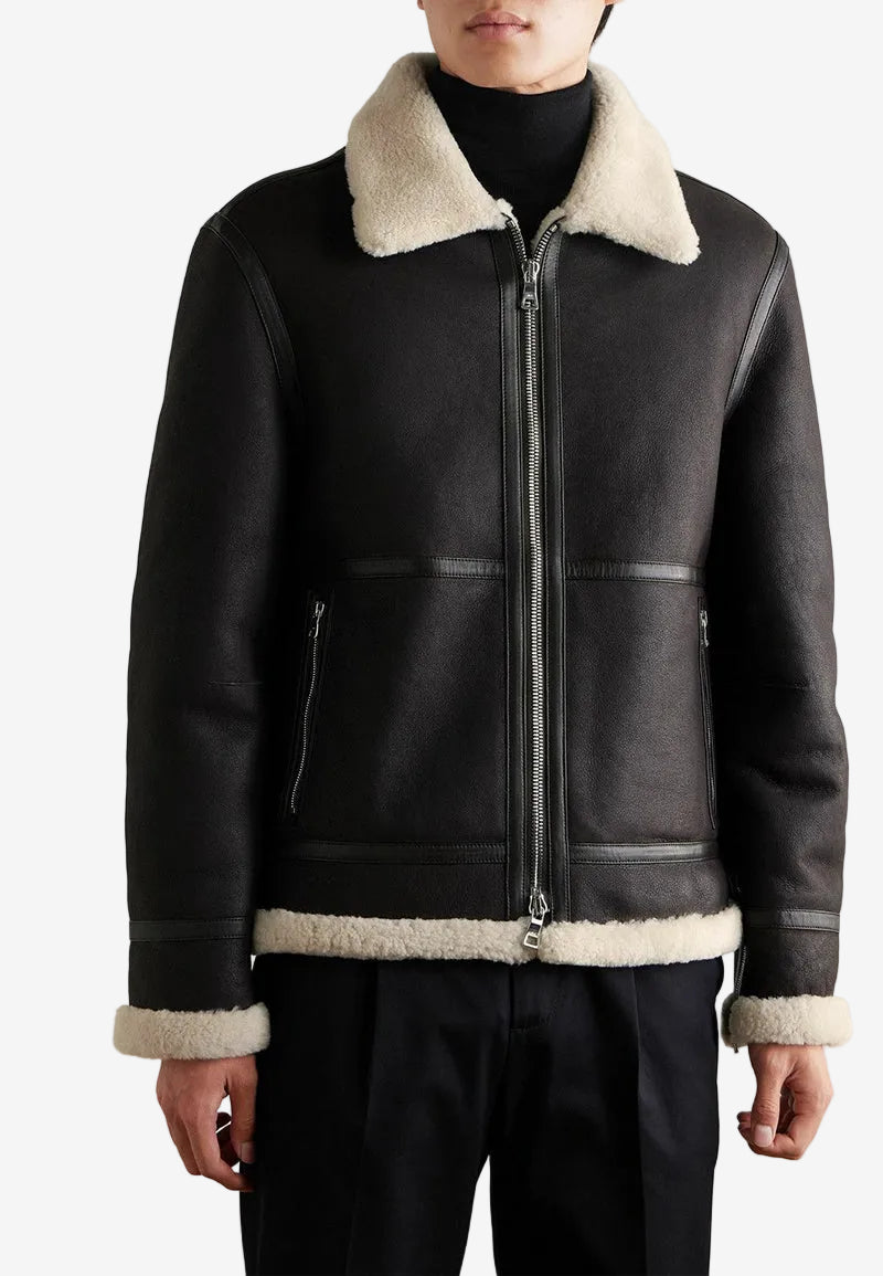 Black leather shearling jacket with beige shearling collar and cuffs on a plain background