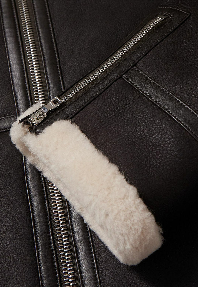 Close-up of a black sheepskin leather vintage shearling jacket with a white fur-lined zipper pull.