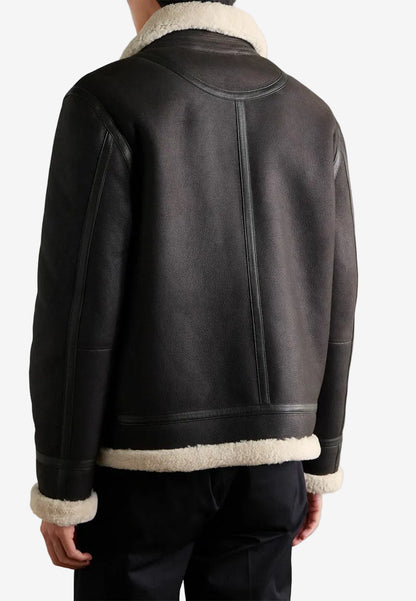 Black leather vintage sheepskin shearling jacket with white fur lining on a plain background