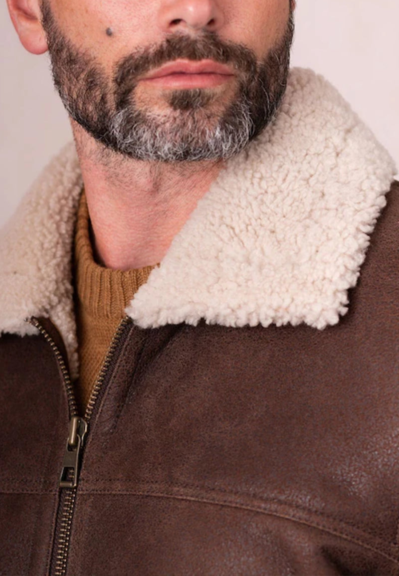 Close-up of a man wearing a brown genuine leather shearling jacket with a white fur collar.