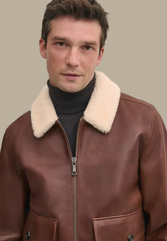 Man wearing a brown leather vintage bomber jacket with a cream fur collar against a beige background