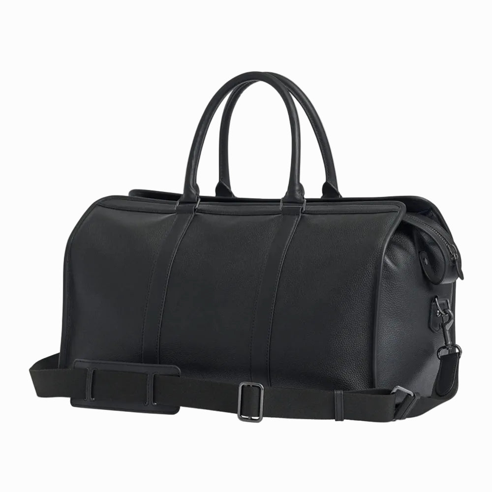 Black leather vintage duffel bag with handles and a strap on a light gray background