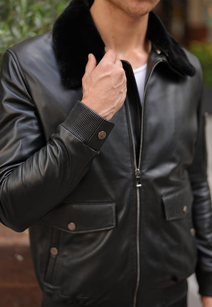 Person wearing a black leather jacket with a fur collar, close-up view.