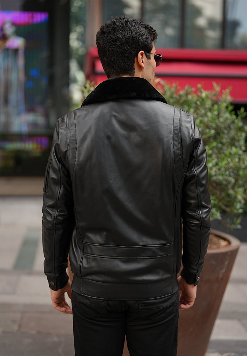 Person wearing a mens black shearling jacket outdoors with a blurred background