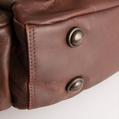 Close-up of a brown leather jacket with metal buttons on a white background