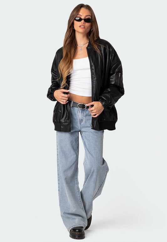 A woman wearing a black oversized leather bomber jacket with black glasses posing for a shoot