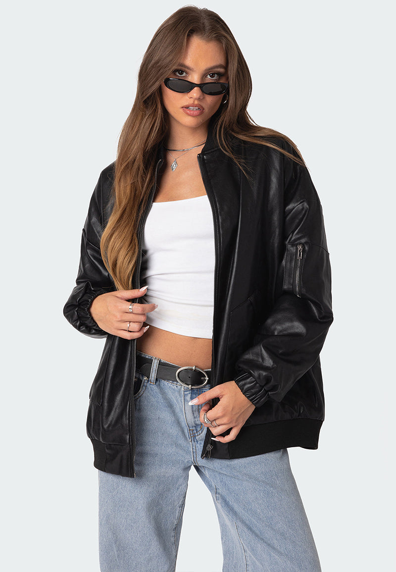 A woman wearing a black oversized leather bomber jacket with black glasses