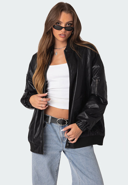 A woman wearing a black oversized leather bomber jacket with black glasses