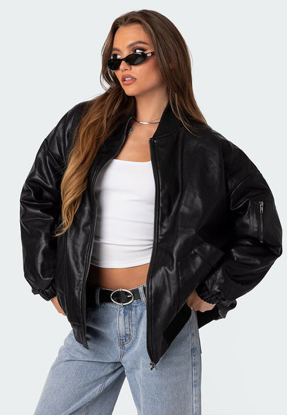 A woman wearing a black oversized leather bomber jacket with black glasses