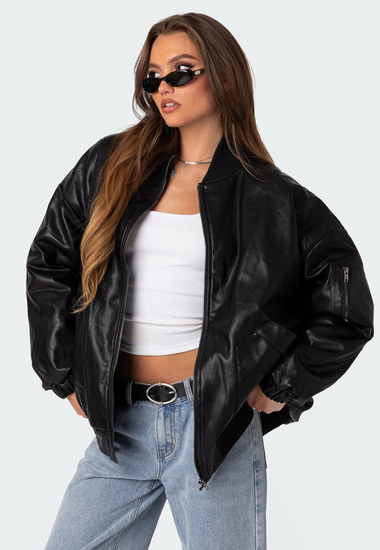 A woman wearing a black oversized leather bomber jacket with black glasses